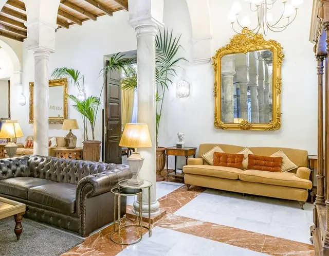 Salón de una suite con paredes blancas y suelo de mármol en tonos blancos y marrones.