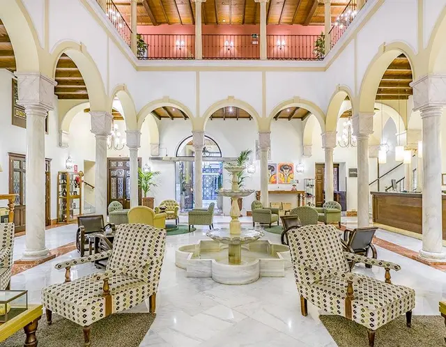 Vista de un amplio vestíbulo o salón común en un edificio histórico con arquitectura andaluza, featuring un patio