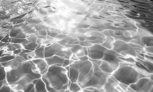 Agua en movimiento con reflejos de luz y ondulaciones en la superficie.